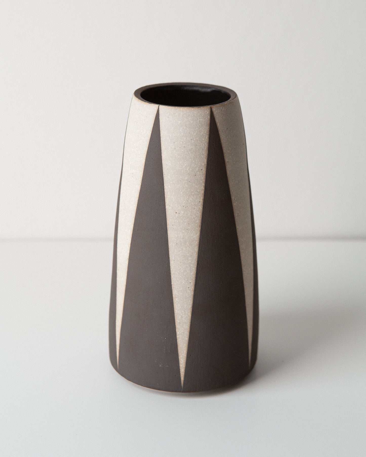 Ceramic vase with black and white striped design on a white background