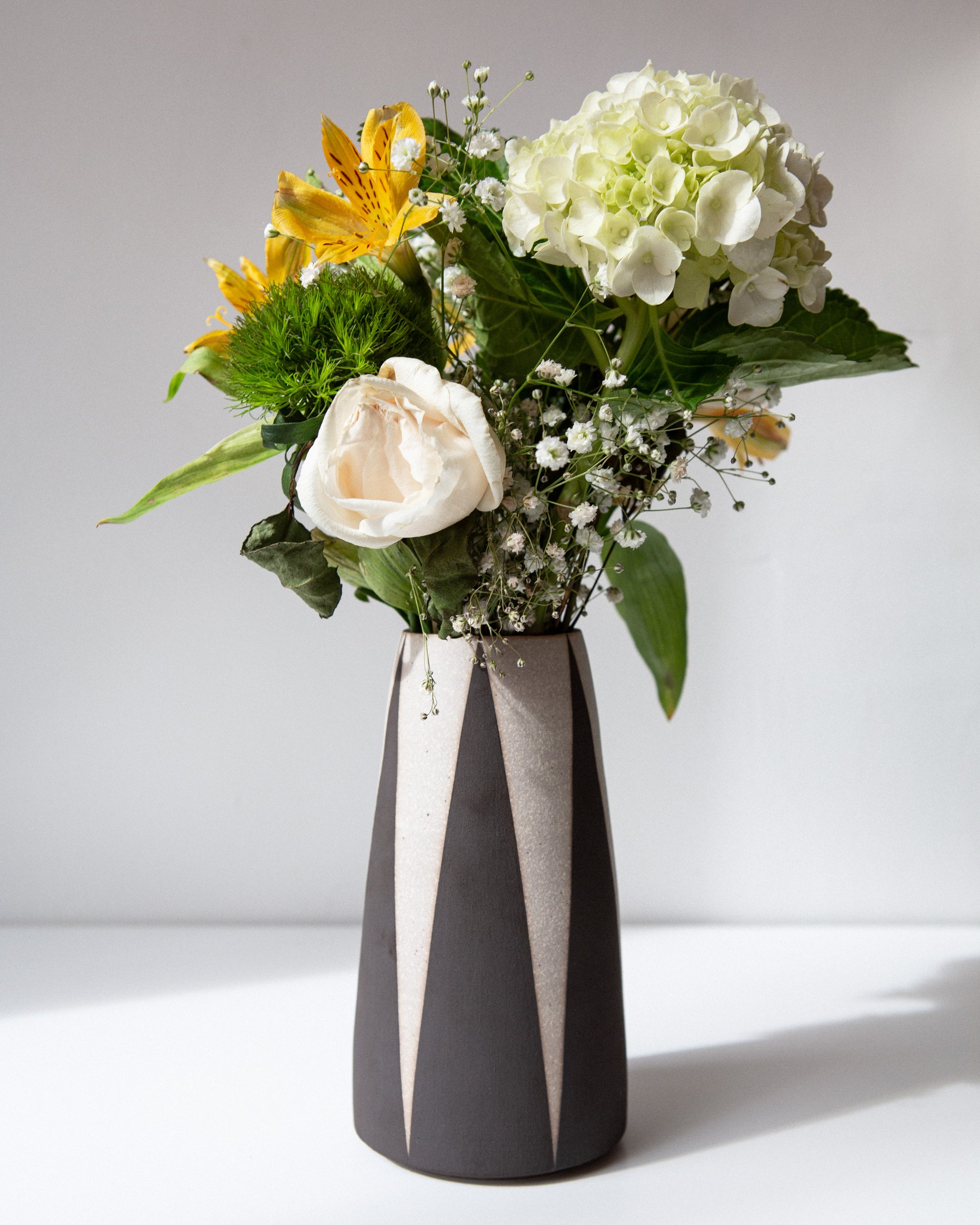 Floral arrangement in a black and white vase on a light background